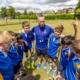 sports teacher chats to group of young students in football gear