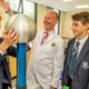 student's hair raises with static electicity as he holds metal ball