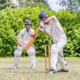 cricket: batsman hits ball as wicket keeper looks on