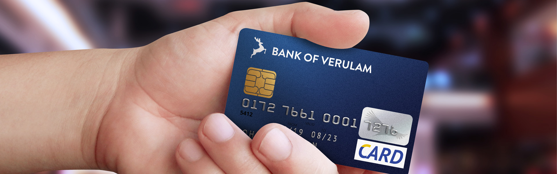 mockup of hand holding bank card. card is in school colours and reads: bank of verulam.