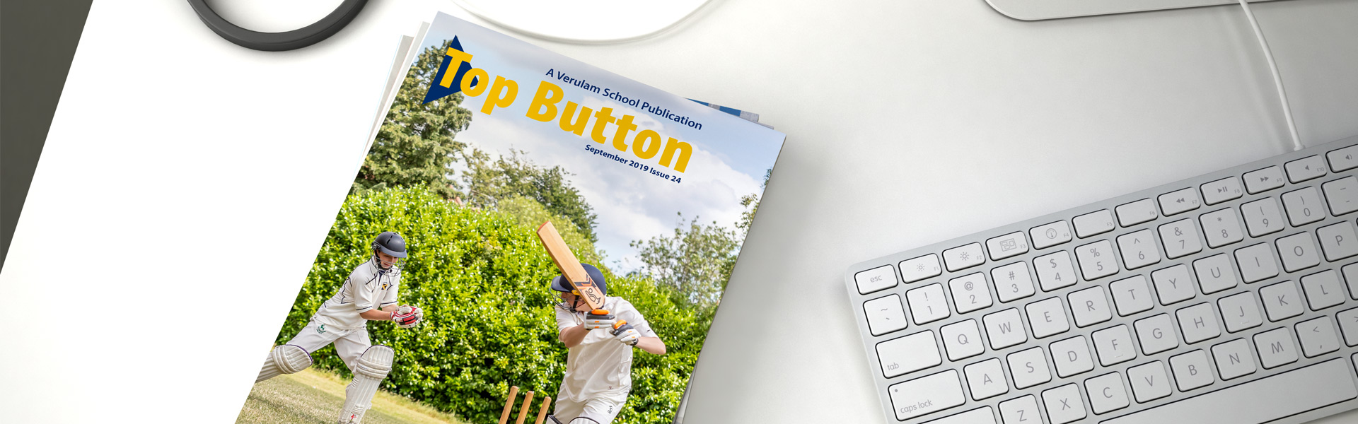 top button magazine sitting next to keyboard on desk