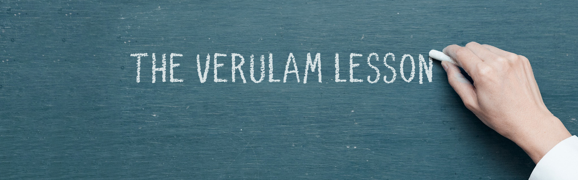 hand writing with chalk on green board: the verulam lesson.